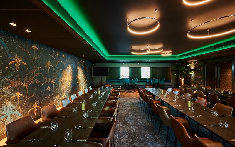 Mat zwart Plameco spanplafond boven eetzaal van restaurant met groene indirecte ledverlichting rondom