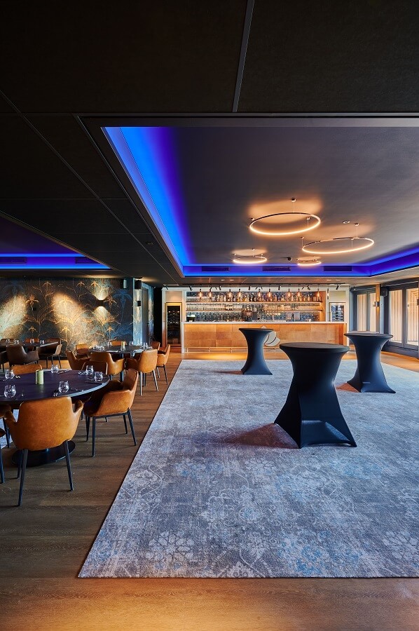Mat zwart spanplafond bij bar met blauwe led-strip om het inliggende plafondelement