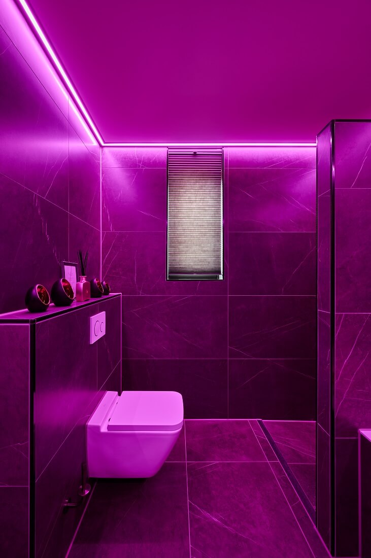 Vochtbestendig Plameco spanplafond in de badkamer met paarsgekleurde RGBWW-verlichting in een led-strip rondom de ruimte