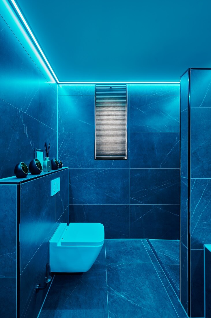 Vochtbestendig Plameco spanplafond in de badkamer met blauwgekleurde RGBWW-verlichting in een led-strip rondom de ruimte